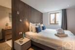 This stunning bedroom boasts a modern design with a wooden accent wall, creating a warm and inviting atmosphere.