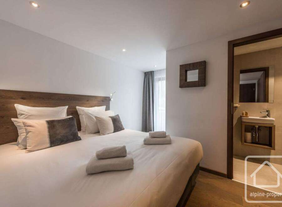 Experience luxury in this stunning bedroom featuring a plush bed with soft linens and decorative pillows.