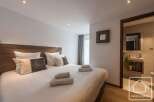 Experience luxury in this stunning bedroom featuring a plush bed with soft linens and decorative pillows.