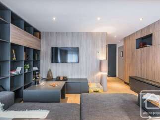 Discover modern living in this stylish property, featuring a sleek entertainment area with a mounted TV and a cozy seating arrangement.