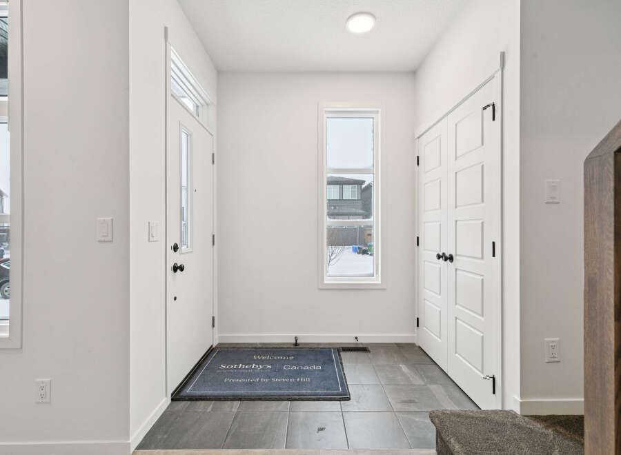 Step into this inviting entryway, featuring a modern design with sleek white doors and walls.