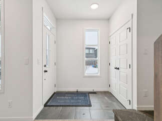 Step into this inviting entryway, featuring a modern design with sleek white doors and walls.