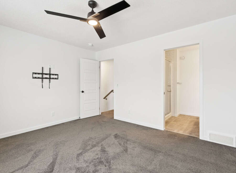 Step into this bright and airy bedroom, featuring a modern ceiling fan and a neutral color palette.