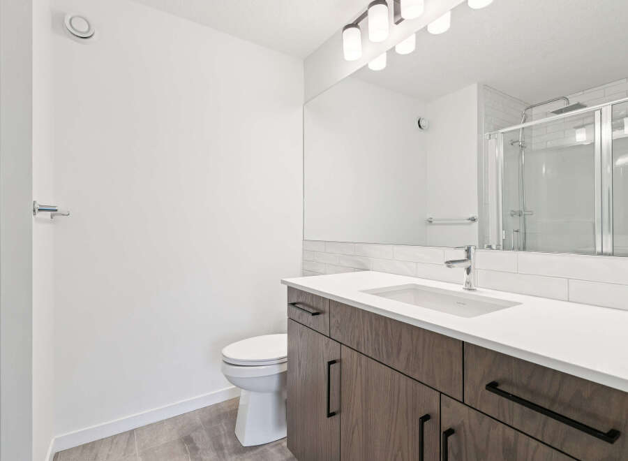 This modern bathroom features a sleek vanity with ample storage and a pristine white countertop.