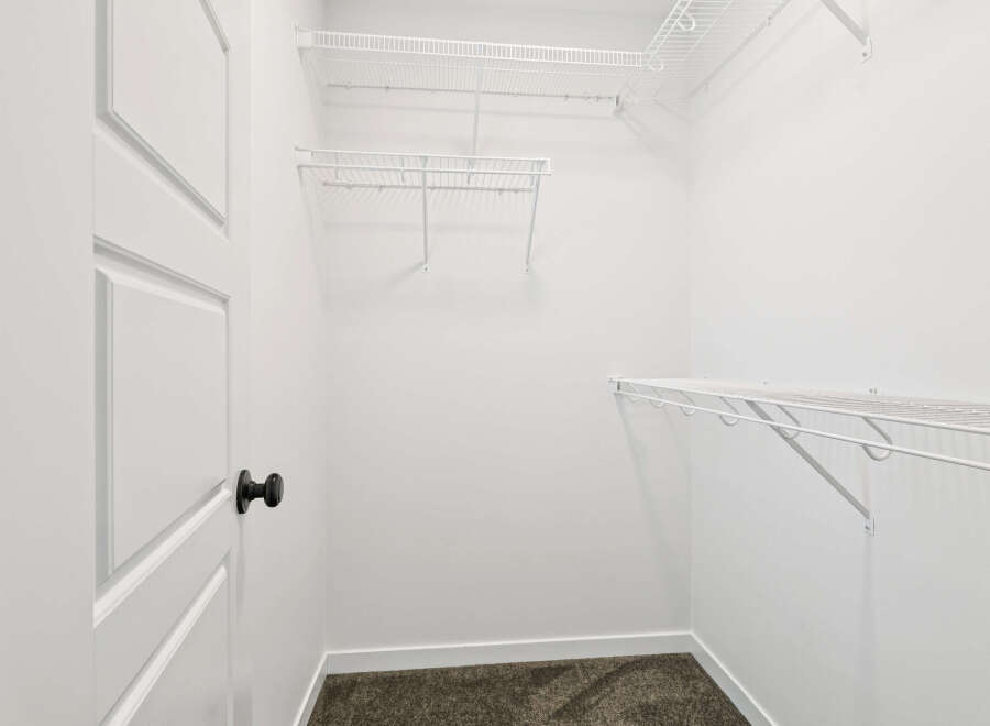 Step into this spacious walk-in closet, offering ample storage with its wire shelving system.