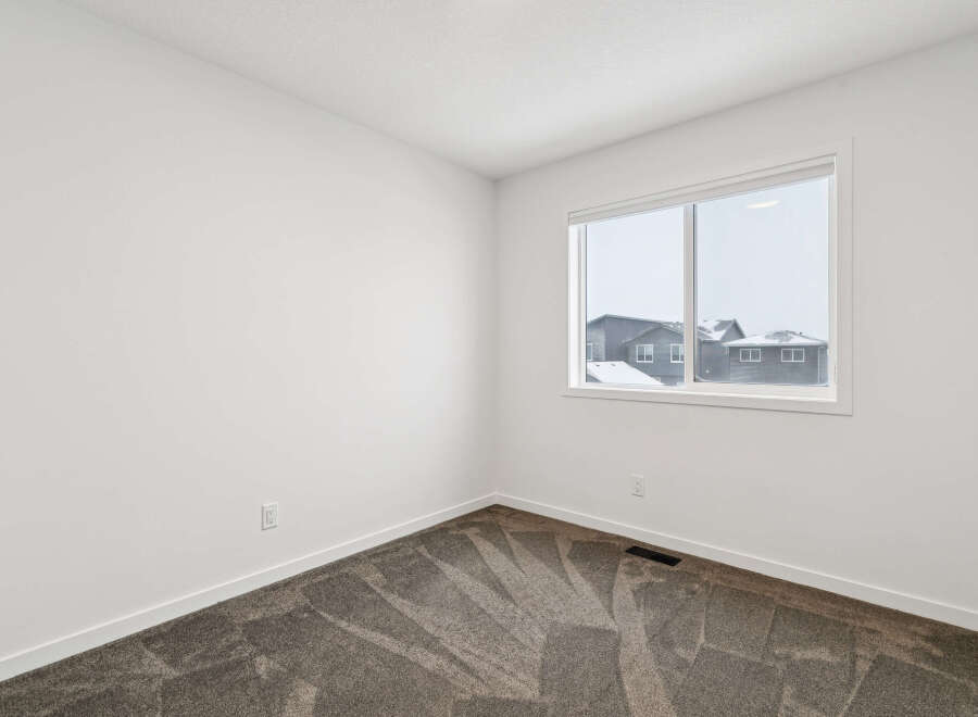 This bright and airy room features neutral walls and a cozy carpet, creating a versatile space.