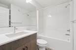 This modern bathroom features a sleek design with a white vanity and a matching white bathtub.