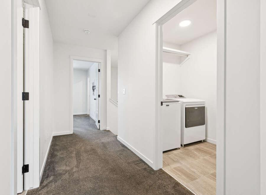 Step into this bright and airy hallway, featuring pristine white walls and elegant dark carpet.