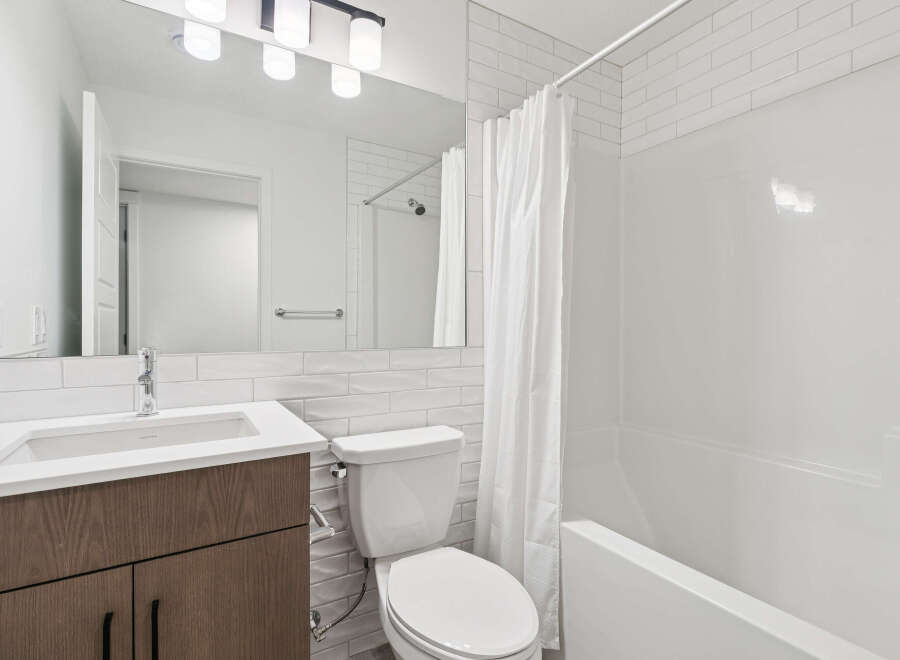 Step into this modern bathroom, featuring sleek white subway tile and a contemporary vanity.