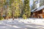 Nestled amidst towering trees and a blanket of snow, this charming property offers a serene escape.