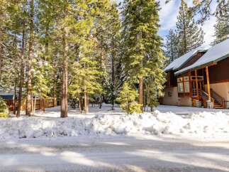 Nestled amidst towering trees and a blanket of snow, this charming property offers a serene escape.