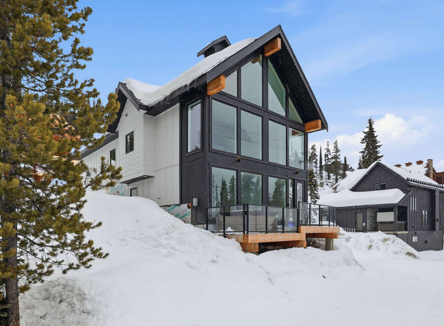 This stunning modern home offers a luxurious mountain retreat with its sleek design and expansive windows.