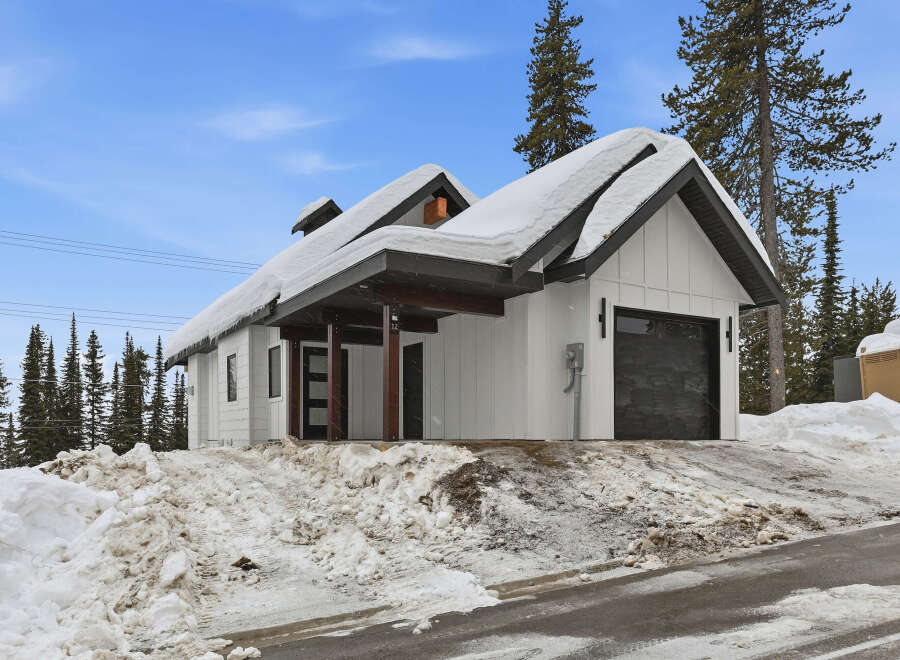 This stunning property boasts a modern design with a snow-covered roof, perfect for a winter getaway.