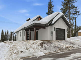 This stunning property boasts a modern design with a snow-covered roof, perfect for a winter getaway.
