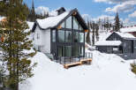 This stunning modern home boasts a striking black and white exterior, perfectly complementing its snowy mountain surroundings.