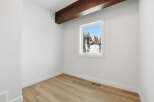 This inviting room features a bright, airy atmosphere with pristine white walls and a warm, natural wood floor.