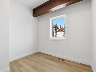 This inviting room features a bright, airy atmosphere with pristine white walls and a warm, natural wood floor.