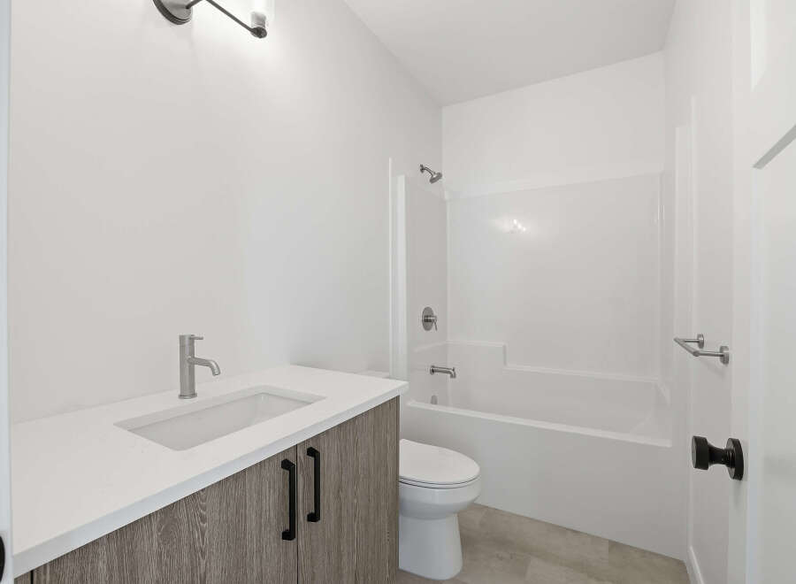 This modern bathroom features a sleek vanity with a white countertop and stylish cabinetry.