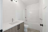 This modern bathroom features a sleek vanity with a white countertop and stylish cabinetry.