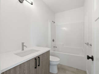 This modern bathroom features a sleek vanity with a white countertop and stylish cabinetry.