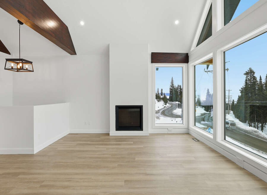 Experience luxury living in this stunning property featuring a modern fireplace, expansive windows, and beautiful wooden beams.