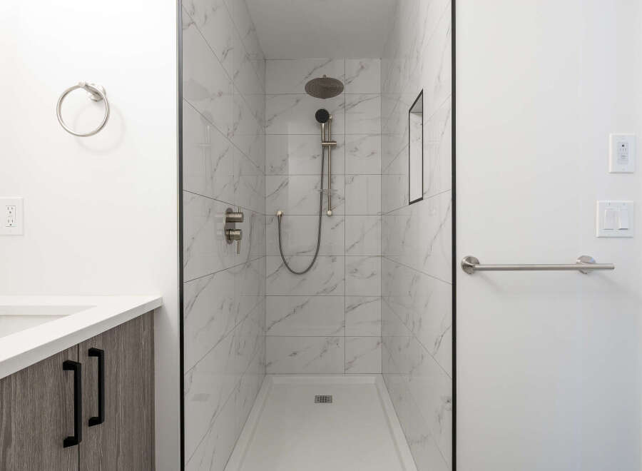 Step into a luxurious bathroom featuring a modern walk-in shower with elegant marble-like tiles.