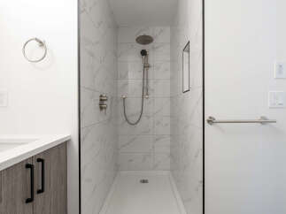 Step into a luxurious bathroom featuring a modern walk-in shower with elegant marble-like tiles.