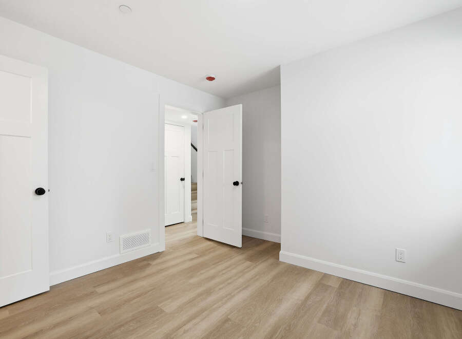 This bright and airy room features pristine white walls and a warm, inviting wood-look floor.