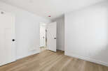 This bright and airy room features pristine white walls and a warm, inviting wood-look floor.