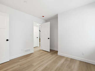 This bright and airy room features pristine white walls and a warm, inviting wood-look floor.