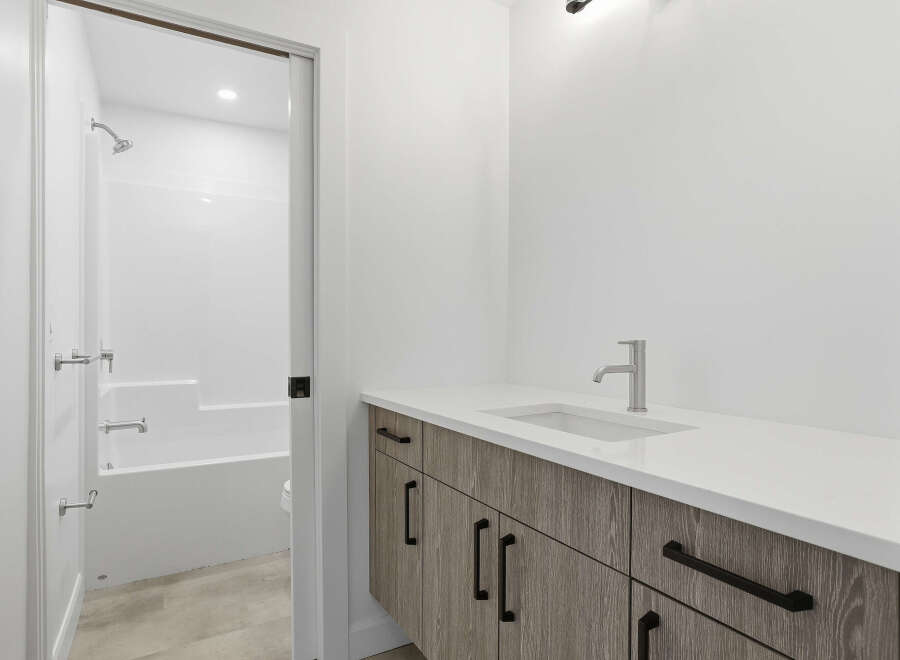 This modern bathroom boasts a sleek design with a pristine white countertop and a stylish faucet.