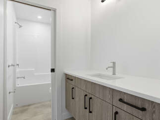 This modern bathroom boasts a sleek design with a pristine white countertop and a stylish faucet.