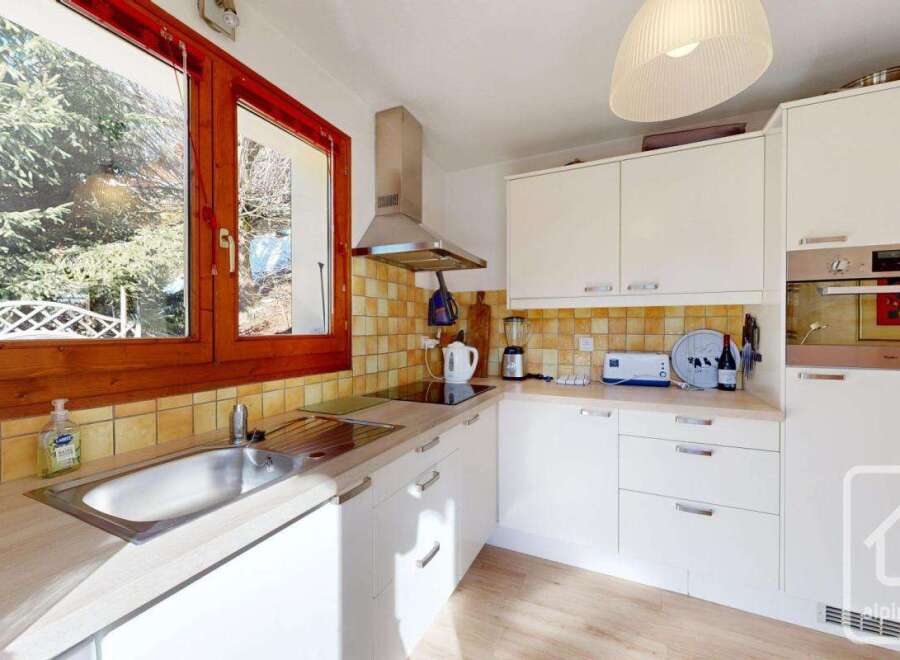 This charming kitchen features a bright and airy design with ample natural light streaming in from the large windows.