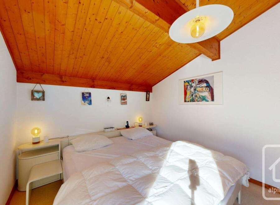 Discover this charming bedroom featuring a cozy ambiance and a unique wooden ceiling.