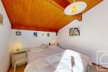 Discover this charming bedroom featuring a cozy ambiance and a unique wooden ceiling.
