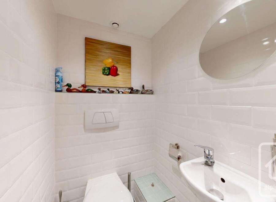 This charming bathroom features a modern design with white subway tiles and a sleek, round mirror.