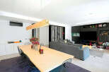 This modern living space features a stunning dining area with a large wooden table and stylish wire chairs.