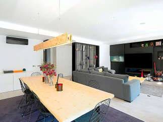 This modern living space features a stunning dining area with a large wooden table and stylish wire chairs.