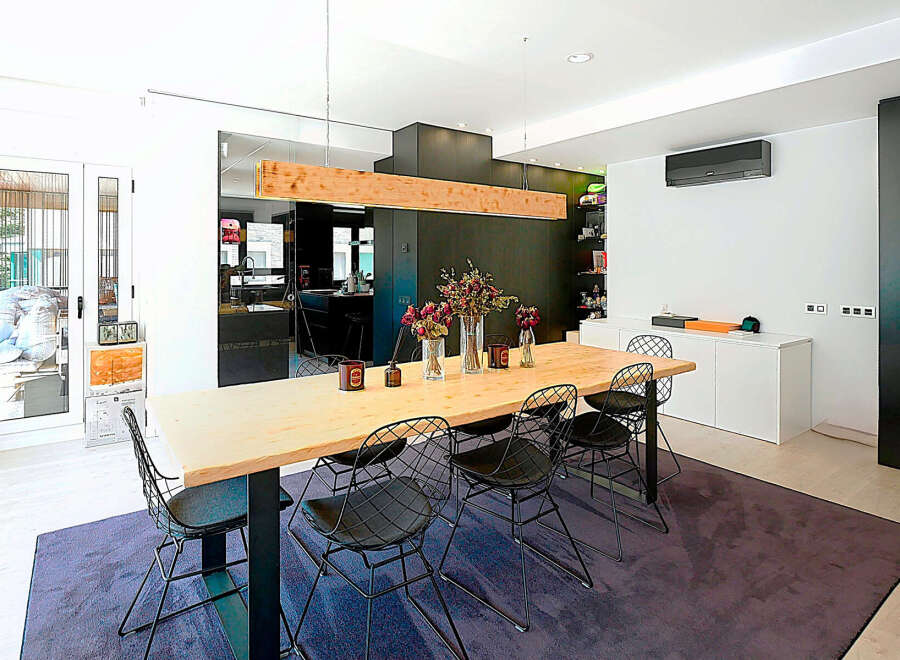 This modern dining room boasts a sleek design with a long wooden table, perfect for hosting gatherings.