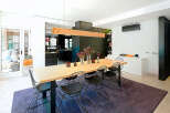 This modern dining room boasts a sleek design with a long wooden table, perfect for hosting gatherings.
