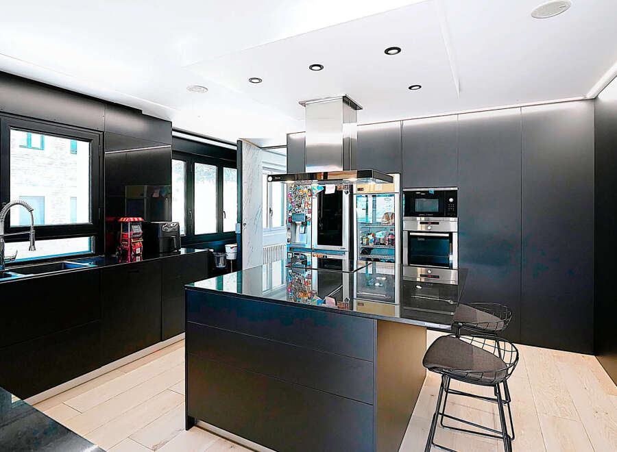 This modern kitchen boasts sleek black cabinetry and countertops, creating a sophisticated and stylish space.