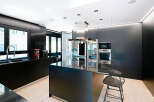 This modern kitchen boasts sleek black cabinetry and countertops, creating a sophisticated and stylish space.