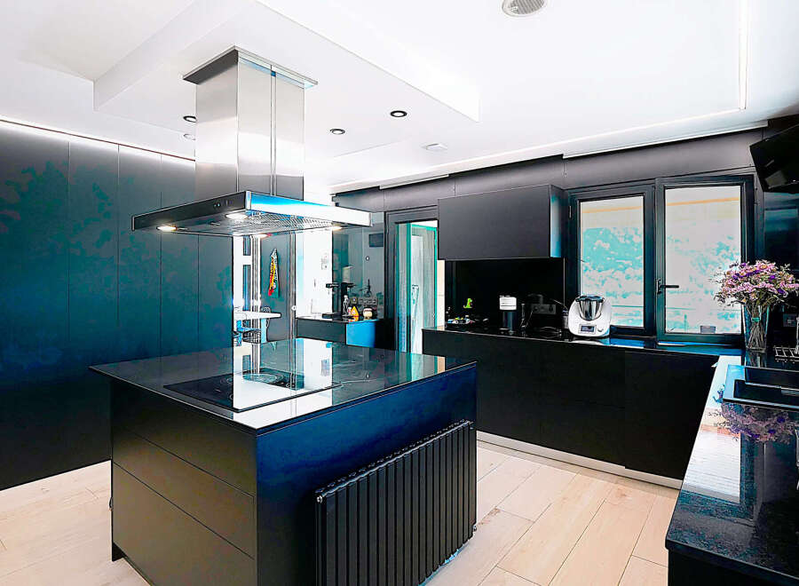 This modern kitchen boasts sleek black cabinetry and a stylish island with a built-in cooktop.