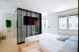 This modern bedroom boasts a sleek design with a stylish partition featuring a mounted TV, creating a unique focal point.