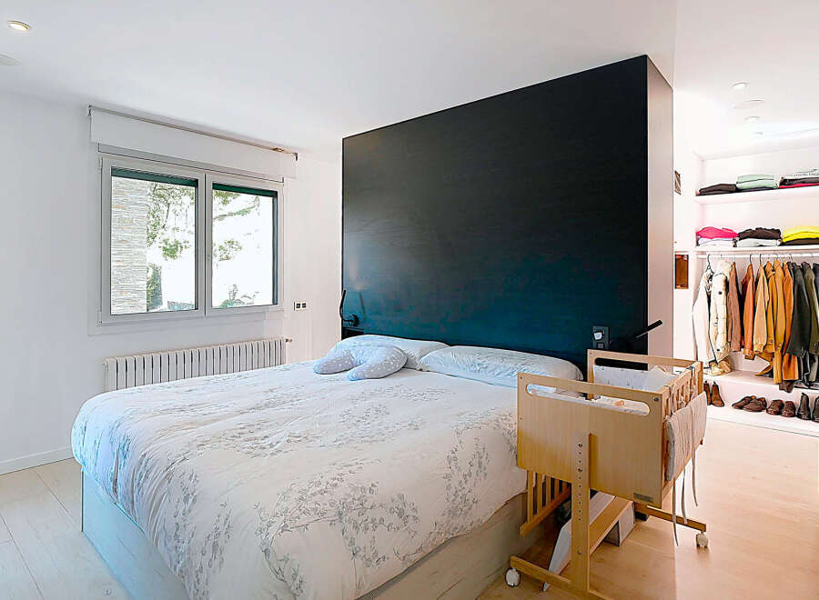 This modern bedroom boasts a sleek design with a striking black accent wall, creating a sophisticated ambiance.