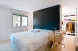 This modern bedroom boasts a sleek design with a striking black accent wall, creating a sophisticated ambiance.