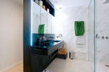 This modern bathroom boasts a sleek, minimalist design with a black double sink and elegant marble-patterned walls.