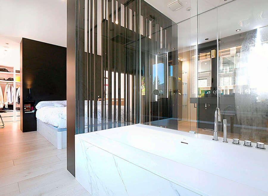 Experience luxury living in this stunning property featuring a modern bathroom with a sleek, white bathtub and a glass-enclosed shower.