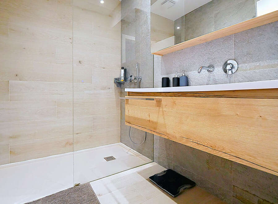 Step into a modern bathroom oasis, featuring a sleek walk-in shower with light-colored wood-look tiles.