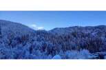 Nestled in a serene winter wonderland, this property offers breathtaking views of snow-covered mountains and lush evergreen forests.